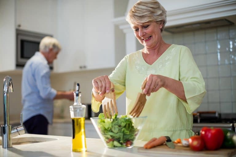 mature woman making salad in kitchen