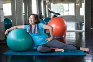 smiling midlife woman in gym with physioball