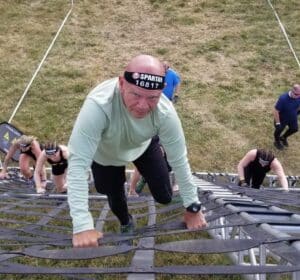 older man climbing an obstacle during a race