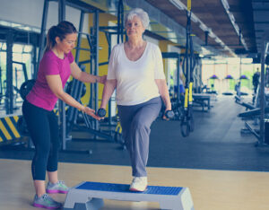 Personal trainer working exercise with senior woman in the gym. Senior woman lift weight.