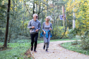 mature couple jogging on trail in woods